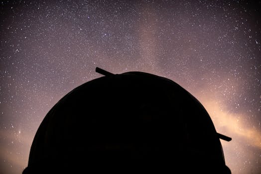 Silhouette of an observatory dome against a dramatic starry night sky.