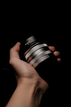 Detailed shot of a hand holding a silver camera lens, showcasing photography equipment.