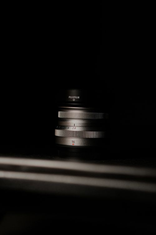 Free Detailed close-up of a Fujifilm camera lens against a dark background, highlighting technological design. Stock Photo