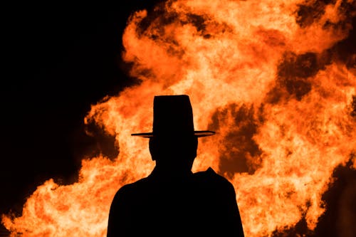 Silhouette of a Person Standing Near a Huge Fire