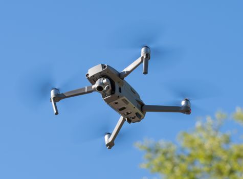 A drone in mid-flight against a clear blue sky, showcasing technology and innovation.