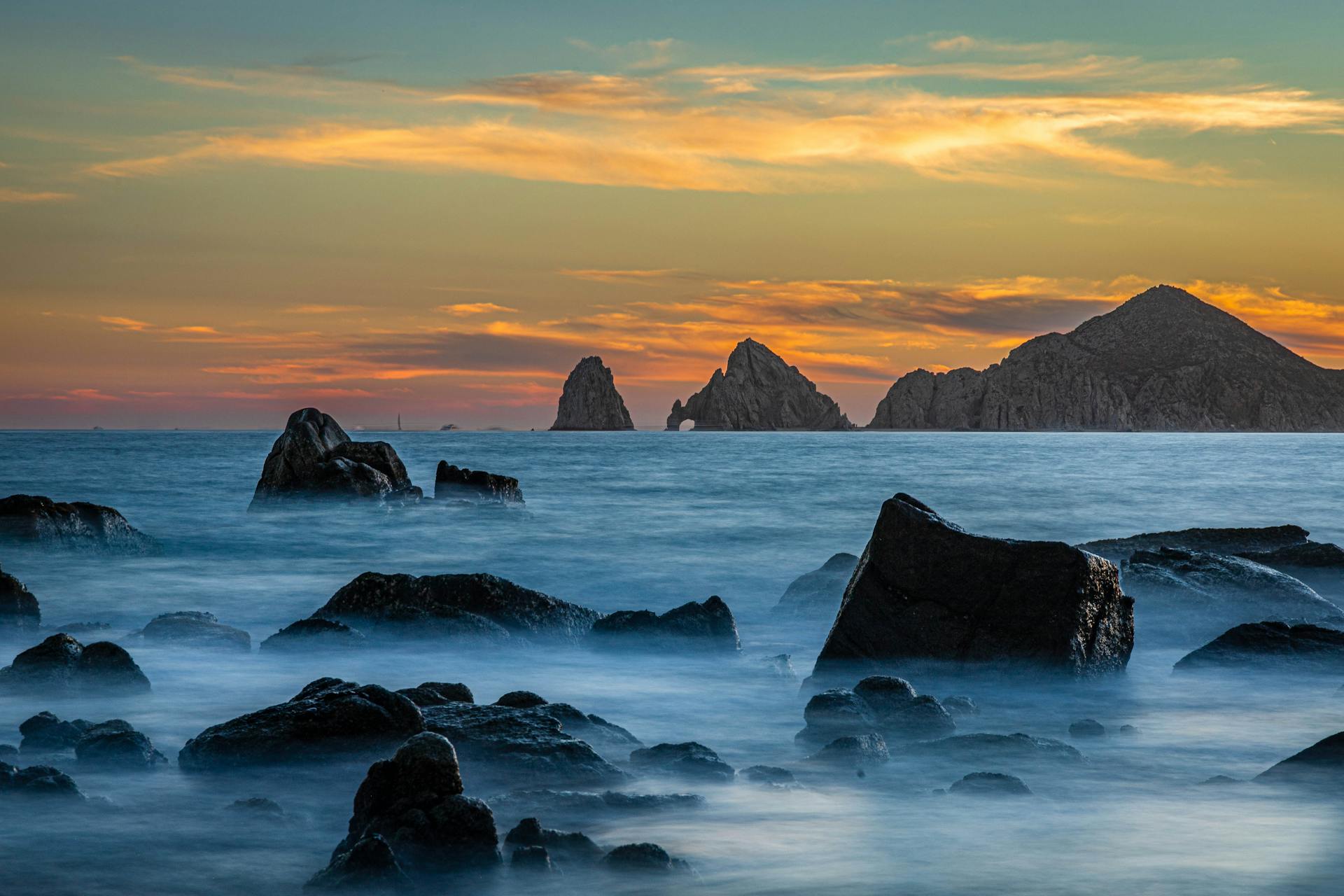 Stunning long exposure of rocky seascape at sunset in Cabo San Lucas, Mexico.