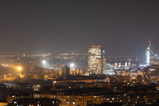 Skyline of Brno city at night with modern architecture and glowing city lights.