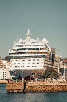 Large luxury cruise ship docked at La Coruña harbor under a clear blue sky.