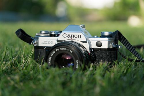 Free A vintage film camera sits atop lush grass, capturing a nostalgic outdoor scene. Stock Photo