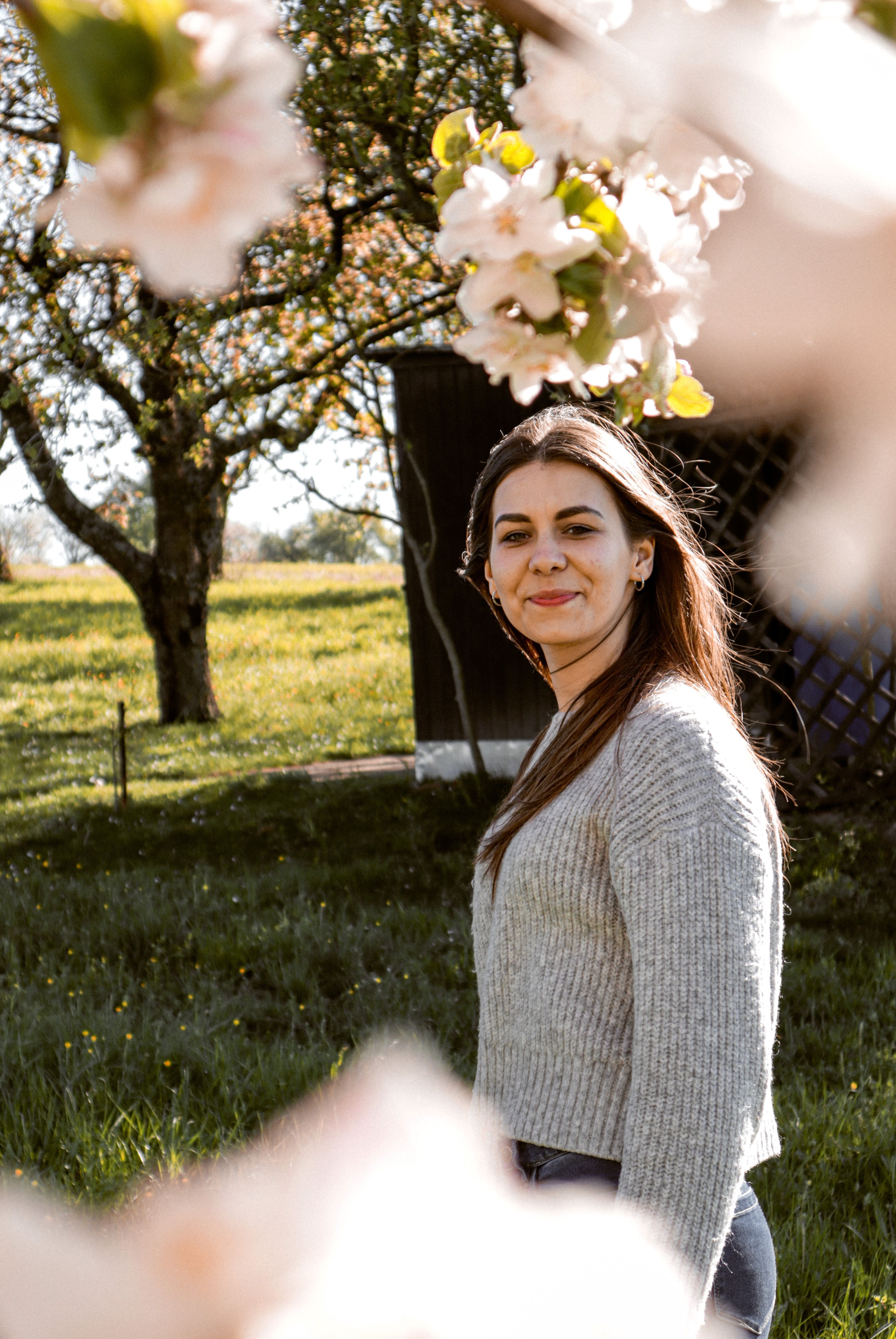 Young woman enjoying a sunny spring day surrounded by blossoms in a park in Bretten, Germany.