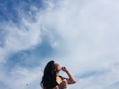 在大西洋城海滩，一位面带微笑的女子正享受阳光明媚的一天，她手拿一杯饮料，头顶是晴朗的蓝天