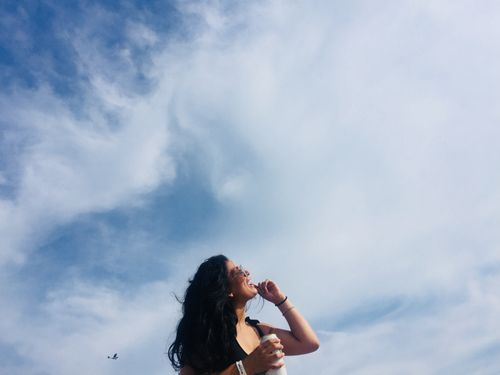 Free Smiling woman enjoys a sunny day at Atlantic City beach, holding a drink with a clear blue sky above. Stock Photo
