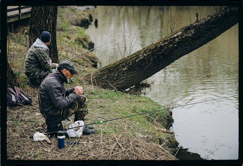 Men Fishing on a Lake Wearing Camouflage Jackets and Sitting on Stool