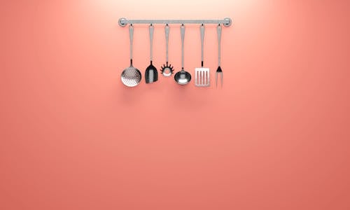 Stainless Steel Cooking Utensils Hanging on Pink Wall