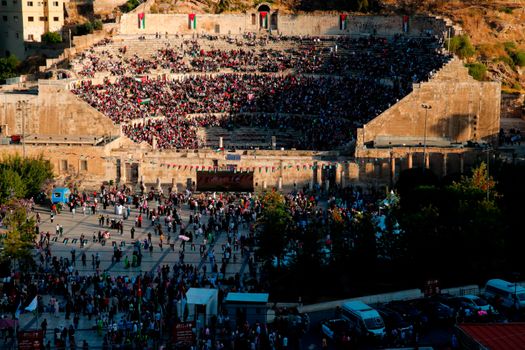 Aerial view of a large crowd gathered at the Roman Theatre in Amman, highlighting its ancient architecture.