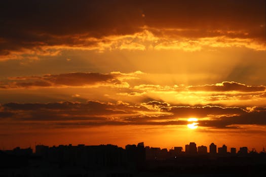 City skyline silhouetted against a vibrant, dramatic sunset with golden clouds.