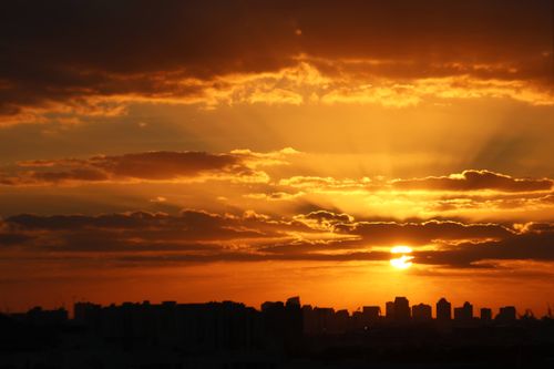 Free City skyline silhouetted against a vibrant, dramatic sunset with golden clouds. Stock Photo