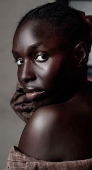 Close-up portrait capturing the elegance of a black woman gazing over her shoulder in soft lighting.