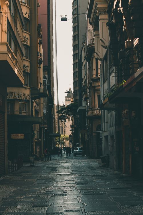 Free A narrow, moody street scene between tall urban buildings, capturing a sense of depth and mystery. Stock Photo