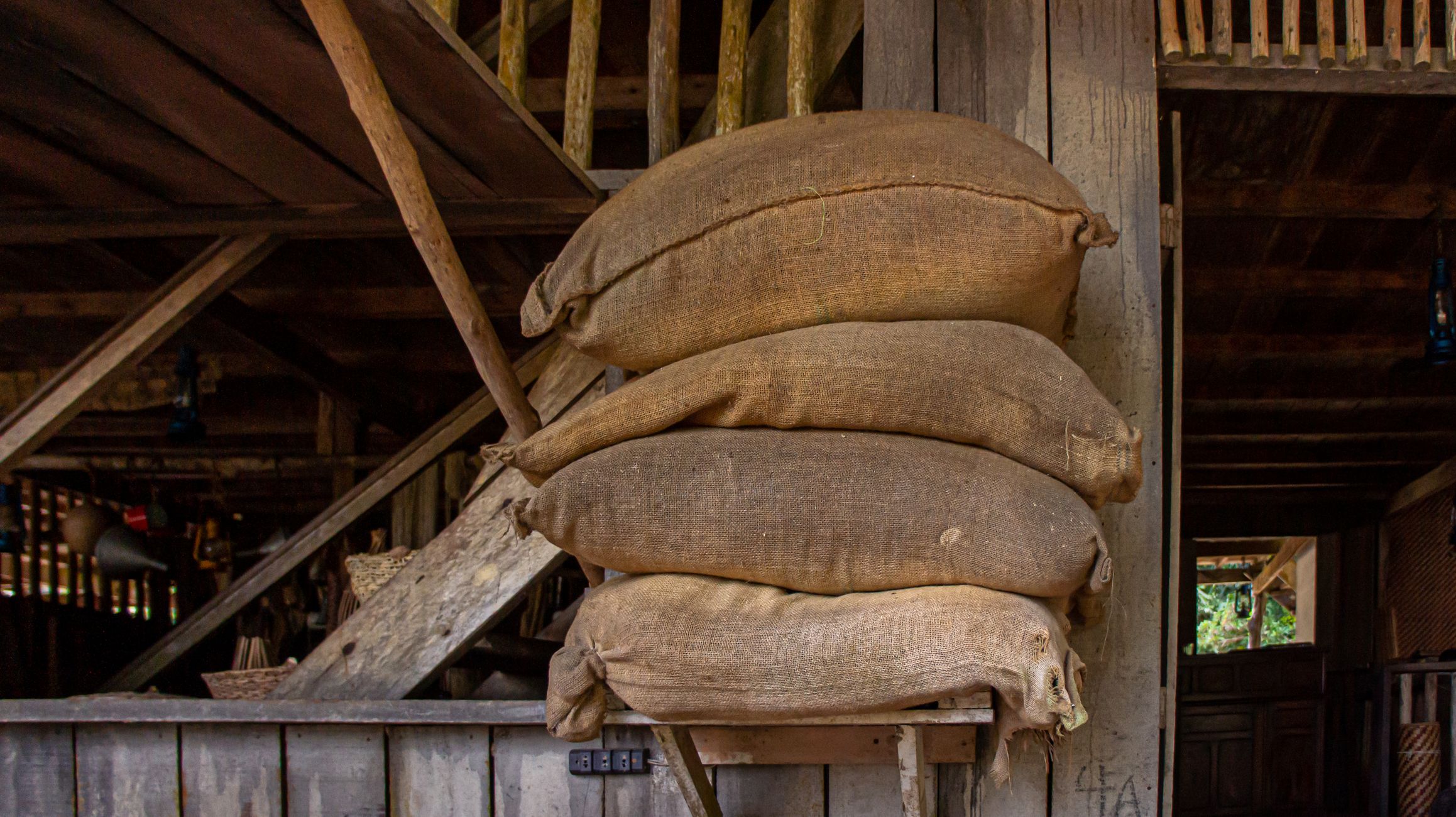 Cozy and rustic barn interior showcasing a stack of burlap sacks against wooden walls.