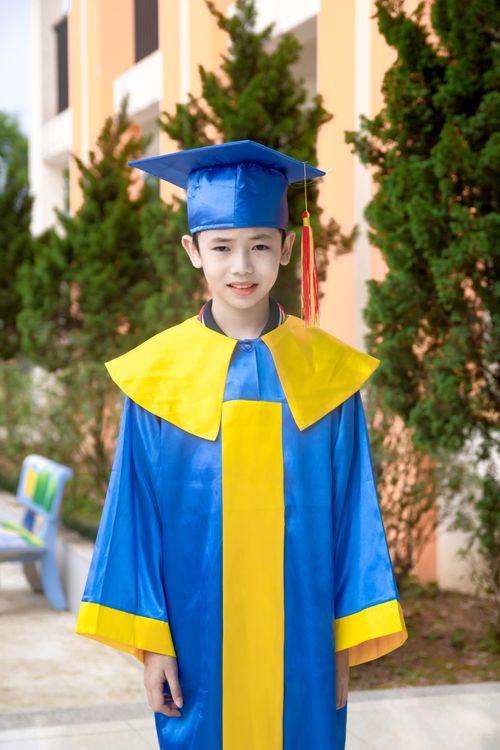 Free Young child in colorful graduation gown and cap outdoors, celebrating achievement. Stock Photo