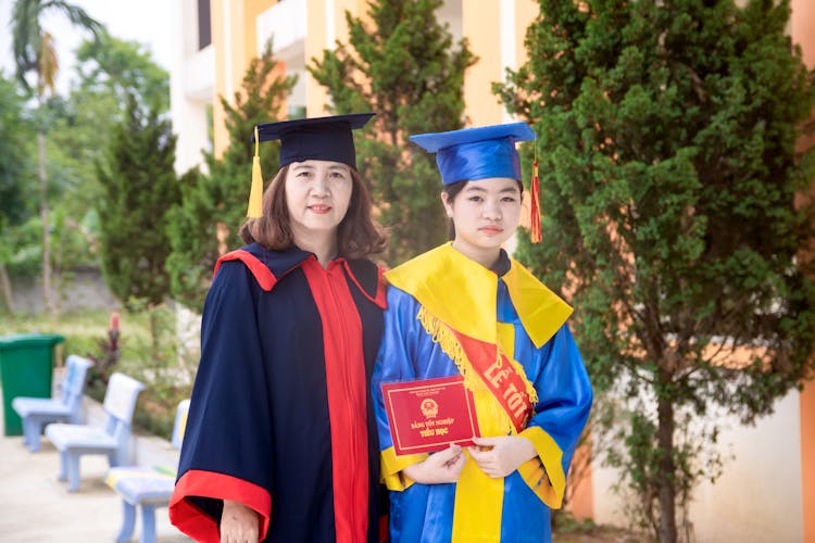 Mother And Daughter In Graduation Gowns 