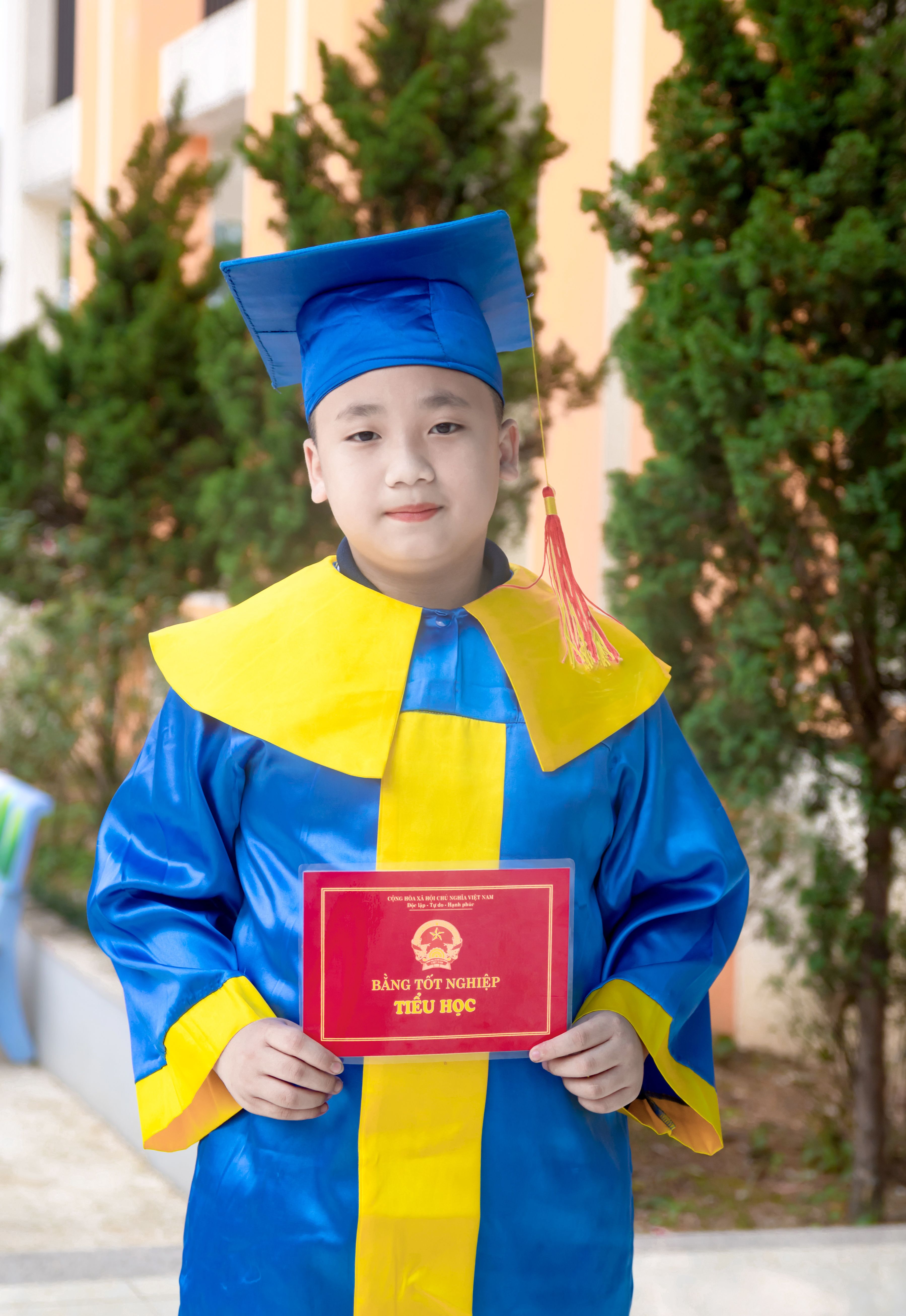 Child in graduation attire proudly displays diploma during ceremony.
