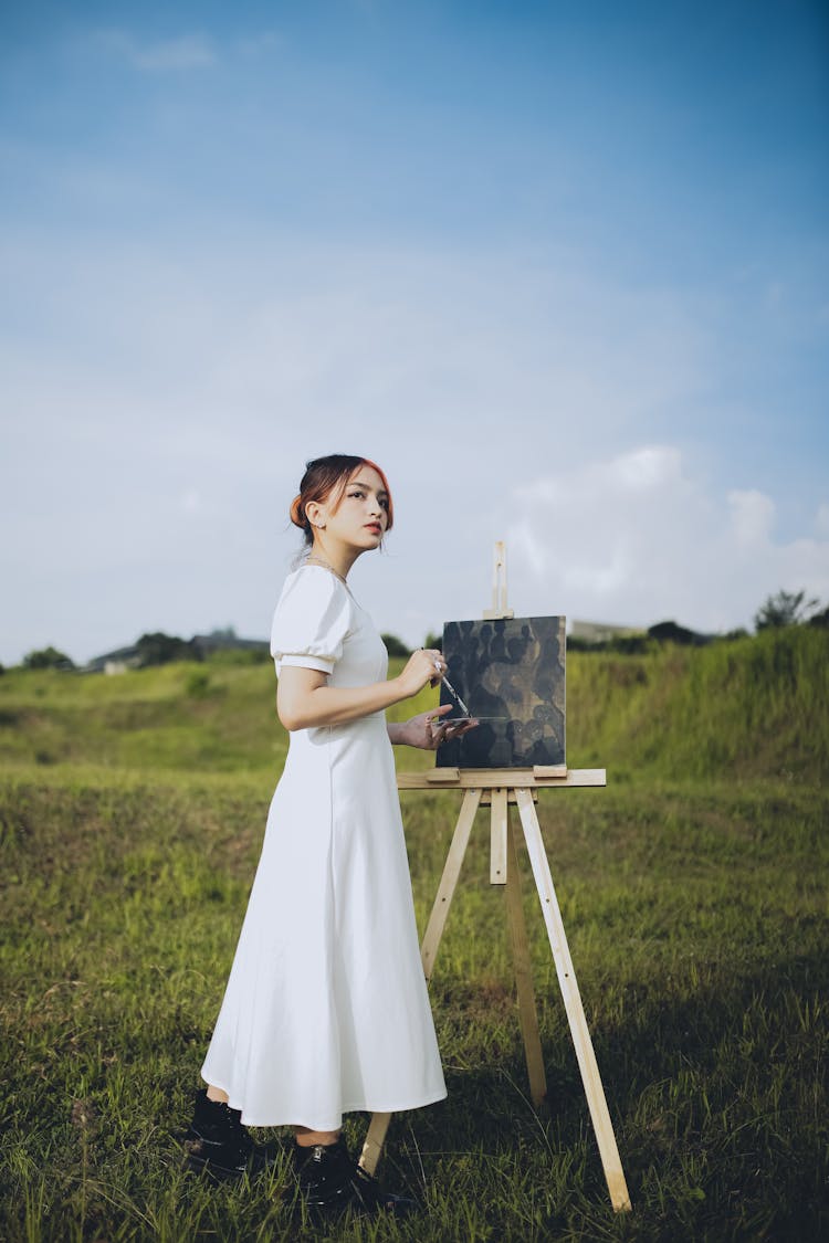 Woman Painting With Easel On Meadow