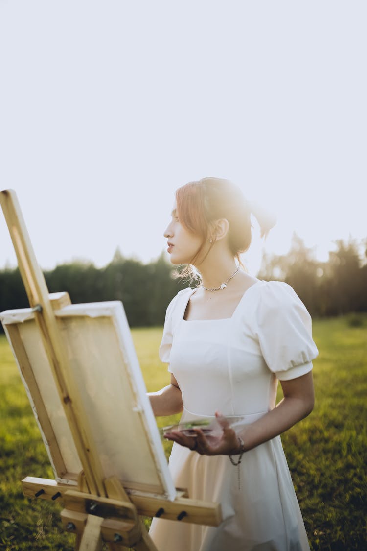 Woman Painting With Easel On Meadow