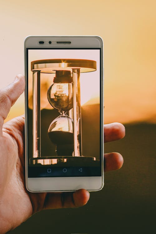 Person Holding Smartphone Showing Hour Glass