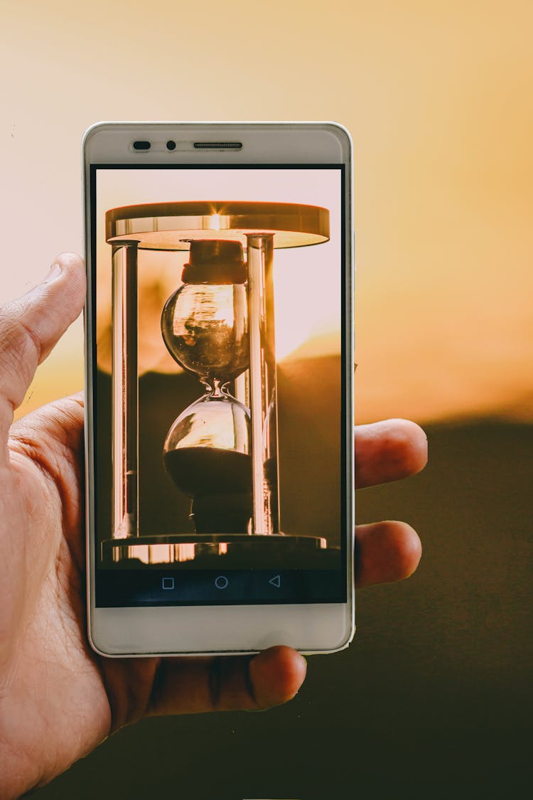 Person Holding Smartphone Showing Hour Glass