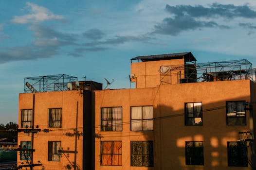 Urban building in Mexico City with warm sunset casting shadows, under a blue sky.