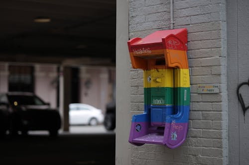 Old Payphone Attached to a Wall Painted in Rainbow Colors 