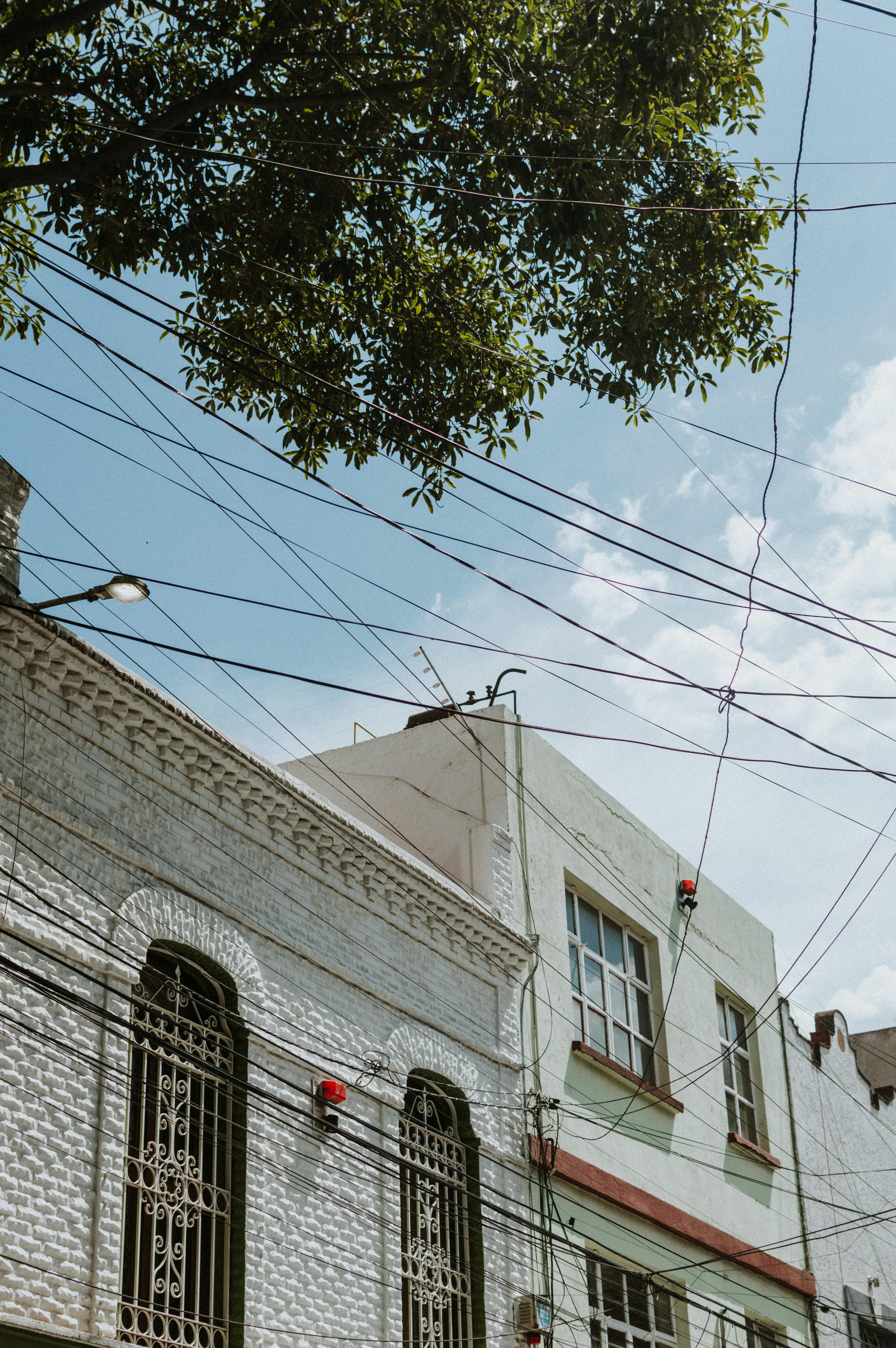 Low-angle view of traditional Mexican architecture with a backdrop of blue sky and urban elements.