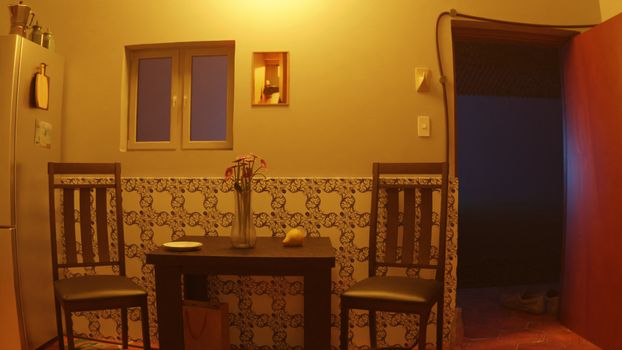 Warmly lit kitchen interior with chairs, table, and vase. Ideal for home decor theme.