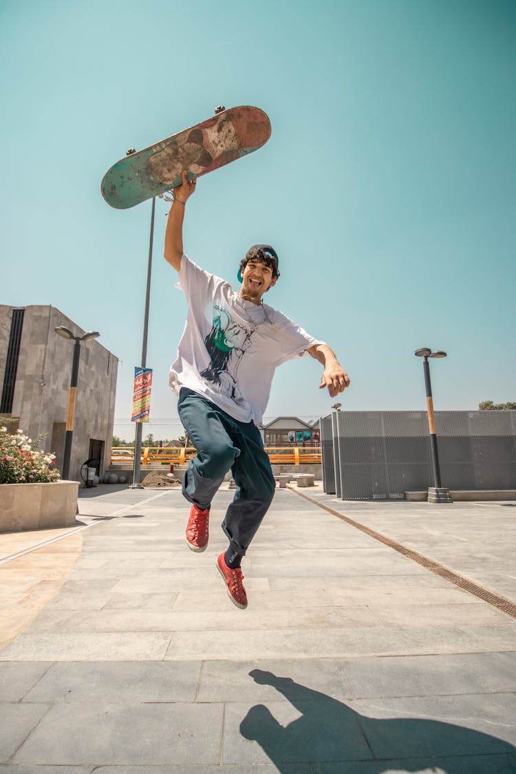 A Man Jumping While Holding His Skateboard 