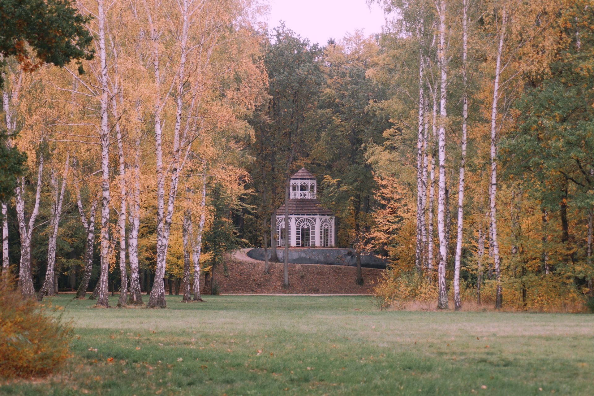 Charming autumn landscape with a rustic gazebo surrounded by colorful foliage in Zatonie, Poland.