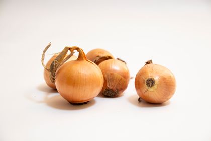 Sweet yellow onions on a pale surface. Photo by Paul Seling on Pexels.