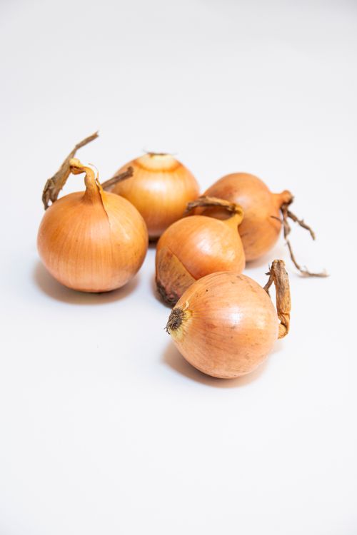 Free High-quality close-up of brown onions displayed on a white surface for culinary use. Stock Photo