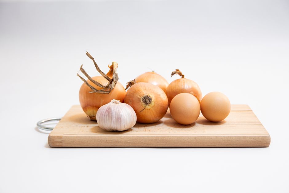 Fresh onions and garlic bulbs arranged together on a dark surface