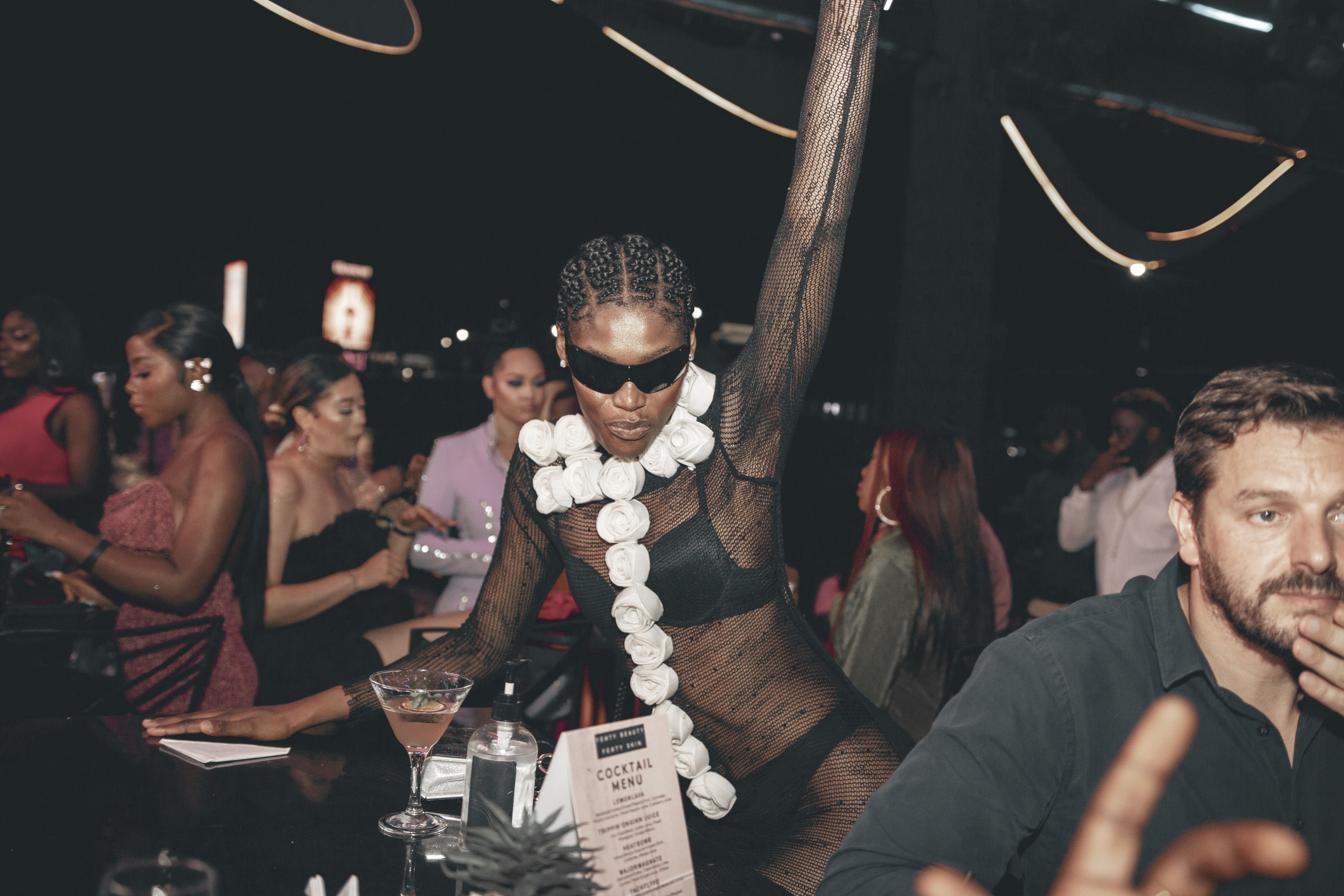Mulher estilosa e expressiva em uma festa ou evento social sofisticado, destacando-se pelo visual marcante e atitude confiante.