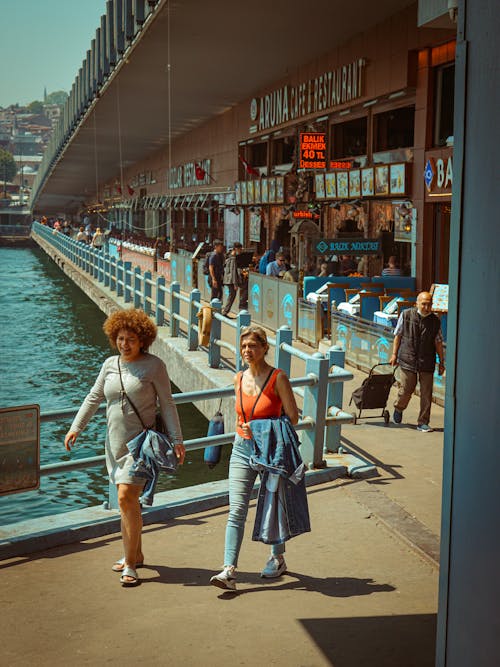 People Walking on Sidewalk near River