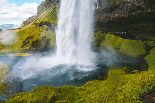 Experience the majestic Seljalandsfoss waterfall cascading over verdant moss in Iceland.