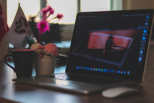 A modern workspace featuring a laptop, coffee cup, and decorative elements on a desk, ideal for remote work environments.