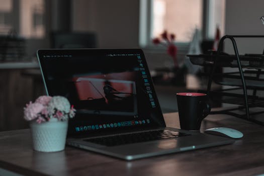 Cozy indoor workspace featuring a laptop, coffee mug, and flowers for a productive environment.