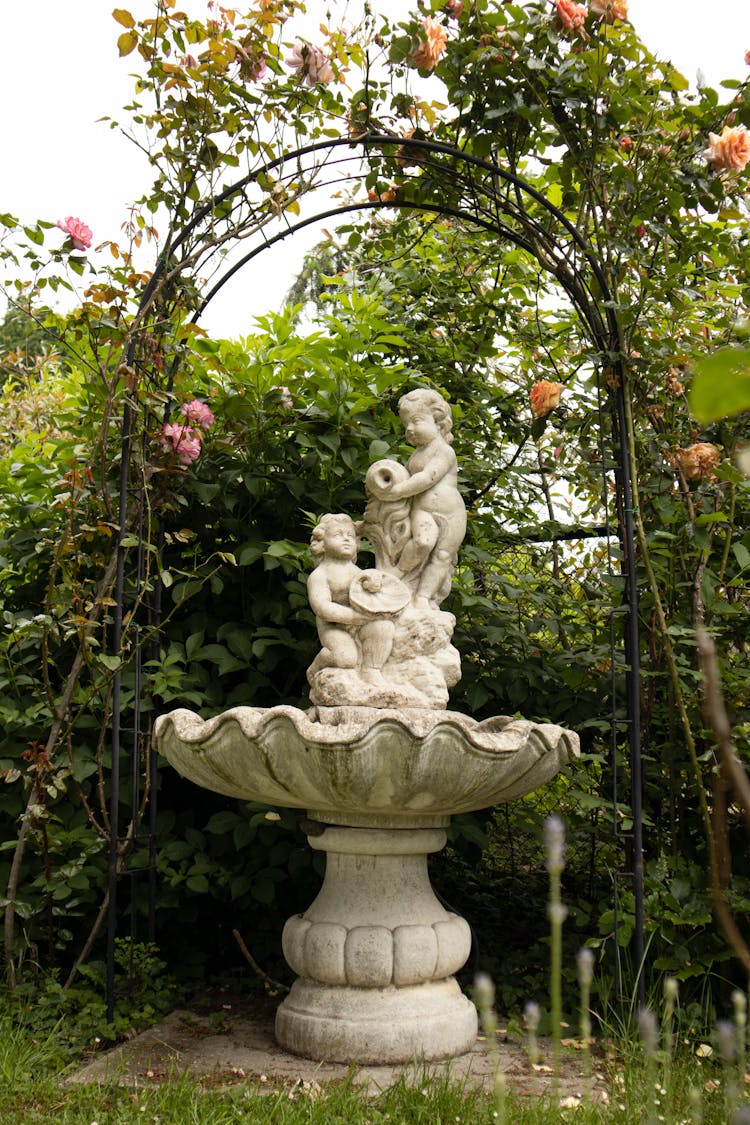 Angel Statue On A Fountain Near Green Plants