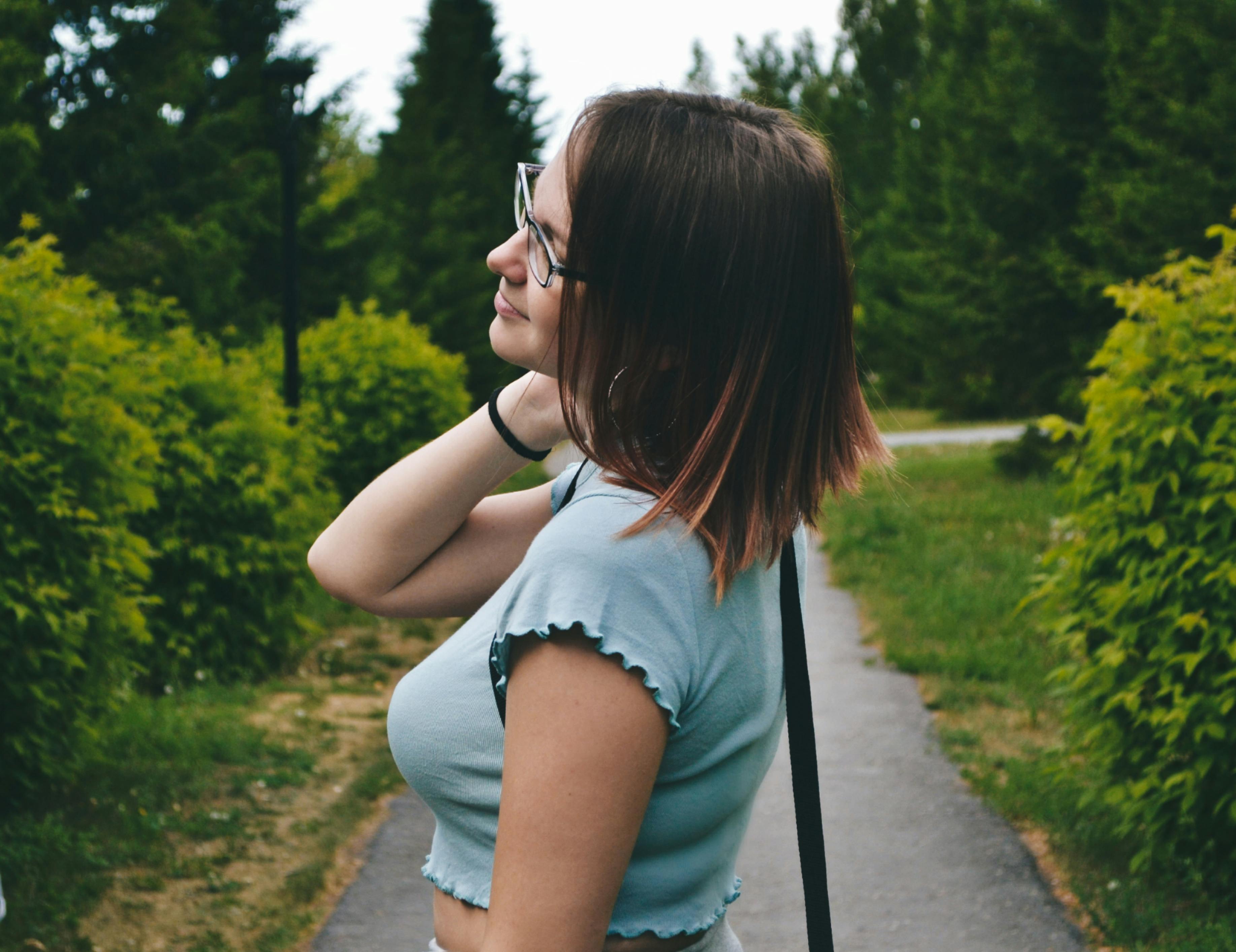 A stylish young woman in blue top and eyeglasses enjoying a summer day outdoors.