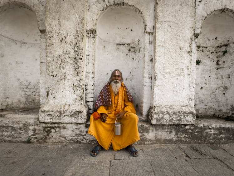 Elderly Man Sitting By Neglected Building