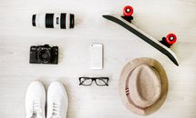 Photography of Black Skateboard, White Iphone 5, Brown Hat, Black Point-and-shoot Camera, and Zoom Lens