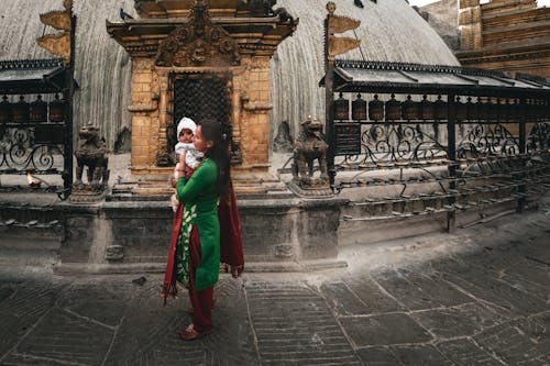 Woman in Traditional Clothes with Baby near Old Temple