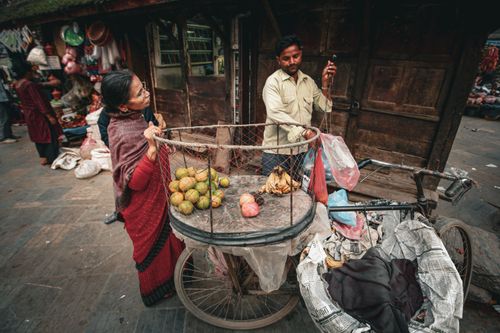 Free A street vendor selling fresh fruits in a bustling urban market setting. Stock Photo