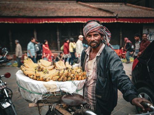 Free A street vendor sells bananas from his bicycle in a bustling outdoor market setting. Stock Photo