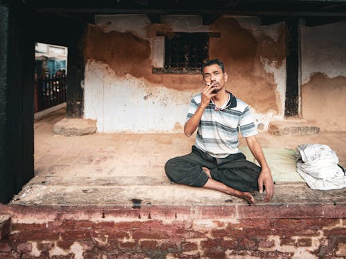 Man Smoking Cigarette outside Neglected Building