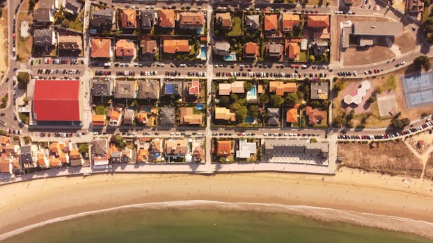 Drone shot capturing a picturesque seaside neighborhood in Nigrán, Spain with vibrant houses and sandy beach.